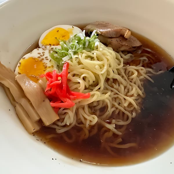 A close-up of Min Sushi's ramen bowl with noodles, broth, sliced pork, soft-boiled eggs, and red ginger.